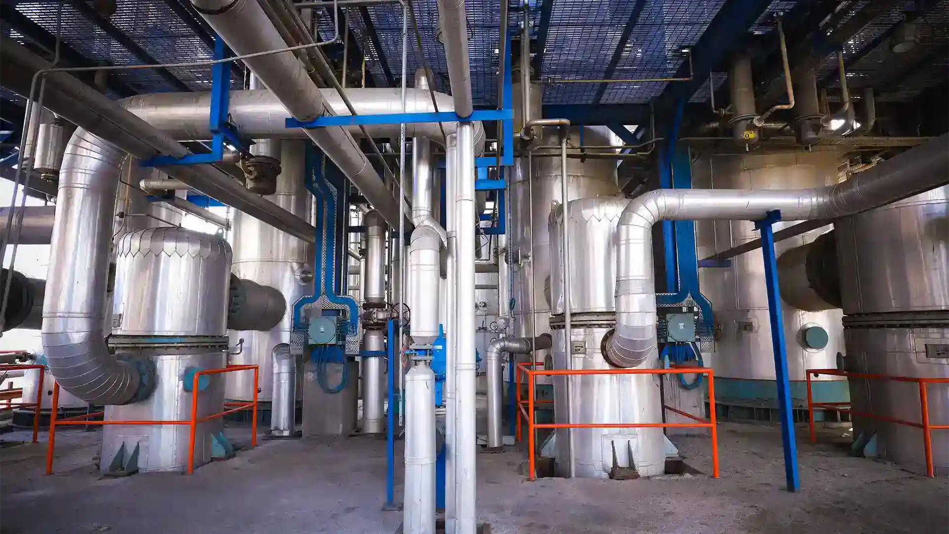 industrial distillery with stainless steel pipes fermentation tanksand safety railing representing an advanced alcohol production facility.